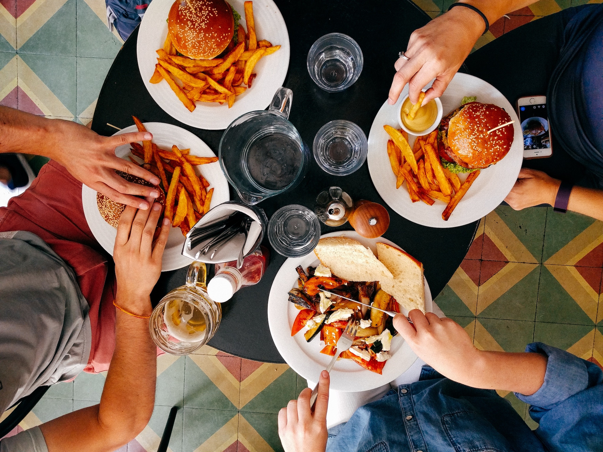 Four people at a table with plates of burgers and frites